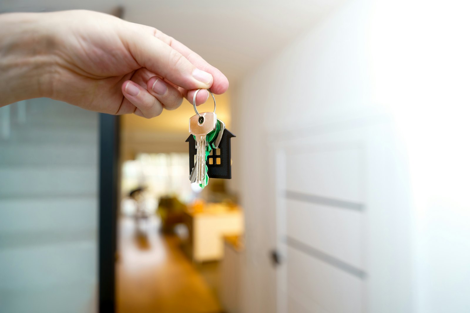 Hand hält einen Wohnungsschlüssel mit Haus-Anhänger